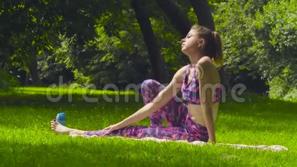 坐在公园草地上的年轻女子视频的预览图