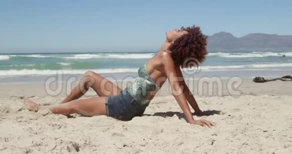 在海滩上放松的年轻非裔美国妇女的侧面景色视频的预览图