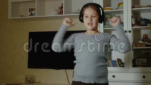 情绪化的小女孩一个留着长发戴着耳机在家里跳舞的小女孩视频的预览图