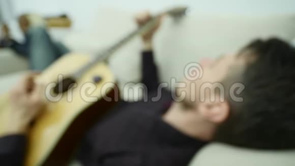 年轻人躺在沙发上弹吉他视频的预览图