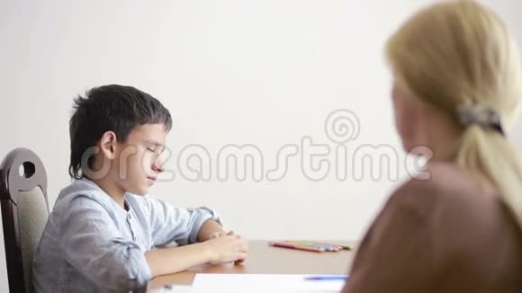 年轻的男孩在与年轻的心理学家交谈时沉默地坐着视频的预览图