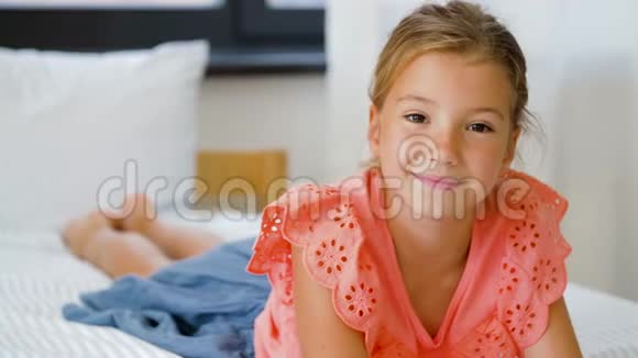 幸福的微笑美丽的女孩躺在家里的床上视频的预览图