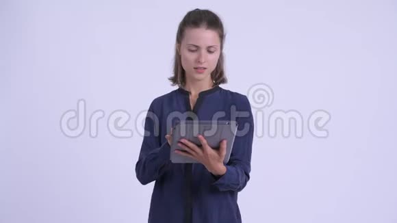 快乐年轻漂亮的女商人用数码平板电脑思考视频的预览图