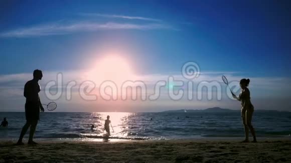 剪影人们在日落时在海滩上打羽毛球视频的预览图
