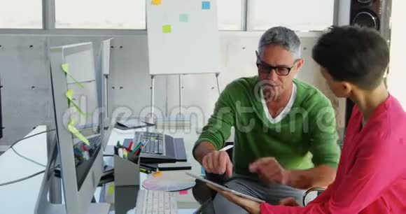 白种人商务人士在办公室的办公桌上讨论数字平板电脑视频的预览图