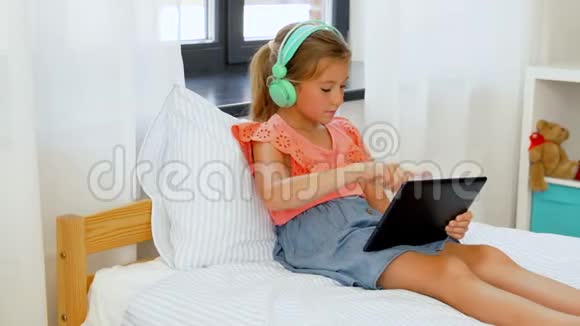 戴着耳机听平板电脑音乐的女孩视频的预览图