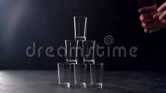 伏特加在黑色背景下从瓶子里倒入玻璃杯视频的预览图