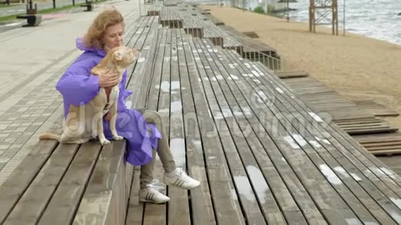 河边沙滩上牵着狗的年轻女子视频的预览图