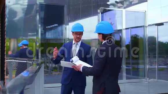 戴头盔的房地产开发商新的办公室建设自信的商人和建筑师在前面说话视频的预览图