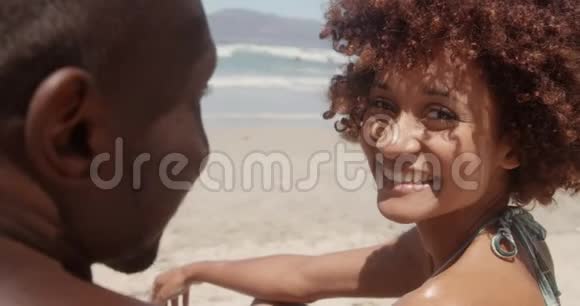 在阳光明媚的海滩上看摄像机的女人视频的预览图
