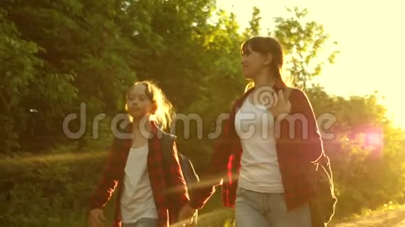 徒步旅行者女孩少女旅行并牵手儿童旅行者带背包的女孩在乡间小路上视频的预览图