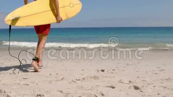英俊的男人拿着冲浪板在水里奔跑视频的预览图