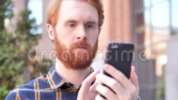 男人在户外坐着用智能手机视频的预览图