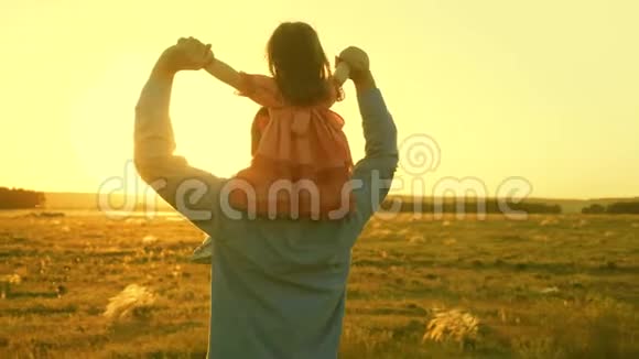 爸爸和他的女儿在阳光下跳舞父亲带着婴儿在夕阳下的肩膀上旅行A视频的预览图