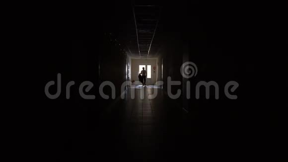 一个男人的剪影穿过黑暗的走廊视频的预览图
