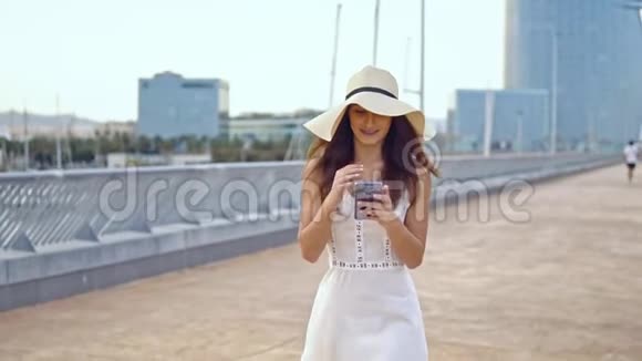 穿着白色裙子戴着帕梅拉帽子走路的漂亮女人视频的预览图