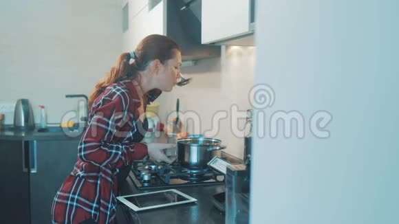 女人在厨房里煮汤锅防止锅里的水数码平板电脑上的食谱视频的预览图