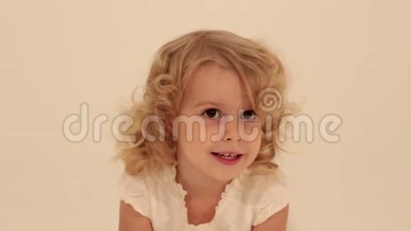 可爱的小可爱的幼儿女孩金发穿着白色连衣裙看着镜头兴奋地跳着视频的预览图