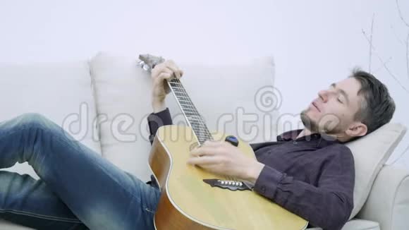 年轻人躺在沙发上弹吉他视频的预览图