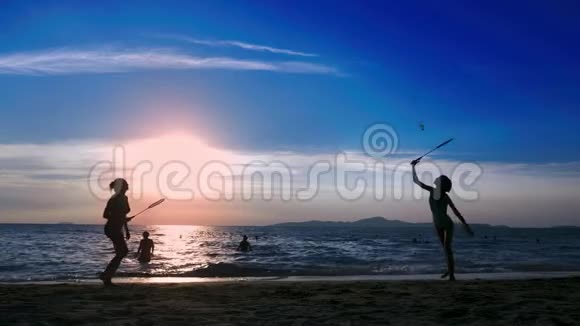 剪影人们在日落时在海滩上打羽毛球视频的预览图