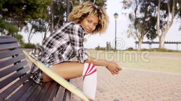 带滑板在长凳上的年轻女人视频的预览图