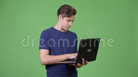 年轻英俊的十几岁男孩用笔记本电脑视频的预览图