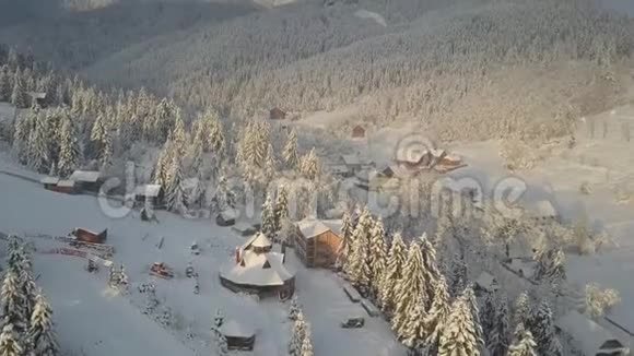 鸟瞰群山中白雪覆盖的房屋冬季的乡村景观喀尔巴阡山村庄在雪中从高处视频的预览图