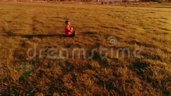 低空径向飞行超过运动瑜伽男子在完美的绿草在山上日落视频的预览图