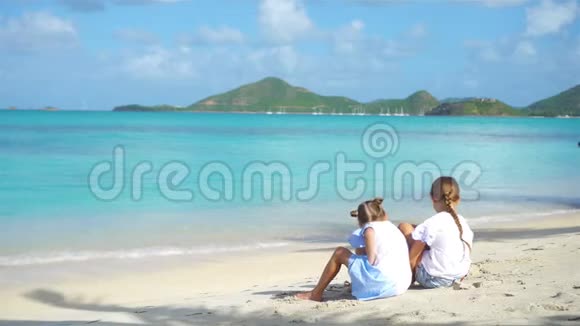 两个快乐的小女孩在热带海滩玩沙玩得很开心视频的预览图