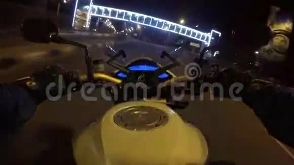 一名骑摩托车的人在傍晚的城镇道路上高速行驶摩托车驾驶的观点视频的预览图