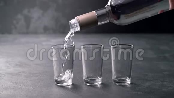 伏特加在黑色背景下从瓶子里倒入玻璃杯视频的预览图