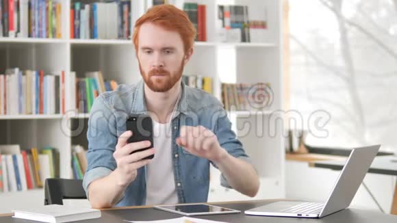在智能手机上使用互联网的临时红发男子视频的预览图