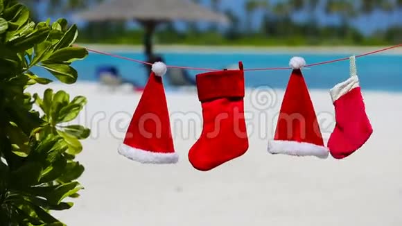 热带海滩上挂着红色圣诞帽和圣诞袜视频的预览图