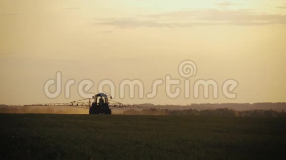 农用拖拉机在日落时用喷雾器除草剂和杀虫剂在田间喷洒农用机械喷洒杀虫剂视频的预览图
