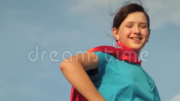 女孩梦想成为超级英雄美丽的女孩超级英雄穿着红色斗篷站在田野上斗篷随风飘扬视频的预览图
