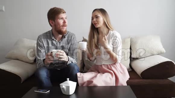 夫妻俩坐在家里的沙发上喝着白茶看着电视视频的预览图