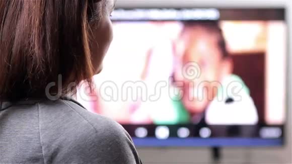 遥控看电视的年轻女子视频的预览图