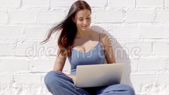 年轻女子在阳光下的笔记本电脑上工作视频的预览图