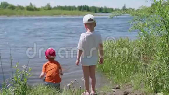 两个孩子在河岸钓鱼美丽的夏日风景户外娱乐活动视频的预览图