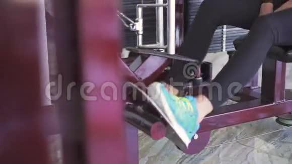 年轻女子在健身房用模拟器训练三头肌视频的预览图