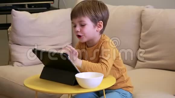 孩子在家里的床上使用平板电脑沙发上可爱的男孩正在看卡通玩游戏从笔记本电脑上学习教育娱乐视频的预览图