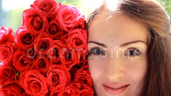 一个年轻美丽的女人带着一束红色玫瑰花的肖像视频的预览图