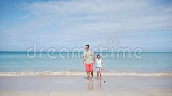 一家人的父亲和小女孩在海滩上玩视频的预览图