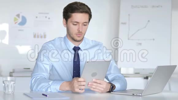 年轻的商人在办公室里用平板电脑视频的预览图