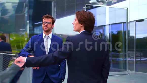 自信的商人在现代办公楼前交谈商人和他的同事银行和金融视频的预览图