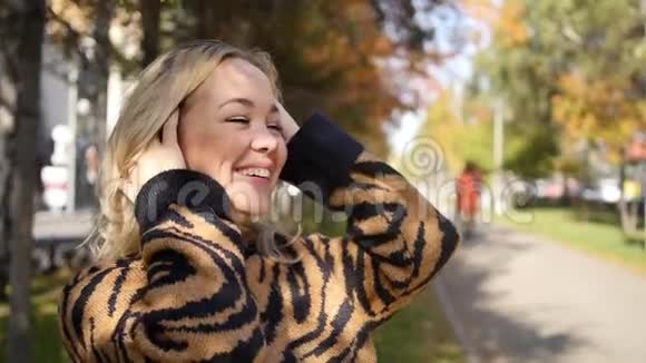 一位美丽的年轻女子在公园里欣赏秋天的肖像秋天公园里迷人的金发女郎视频的预览图