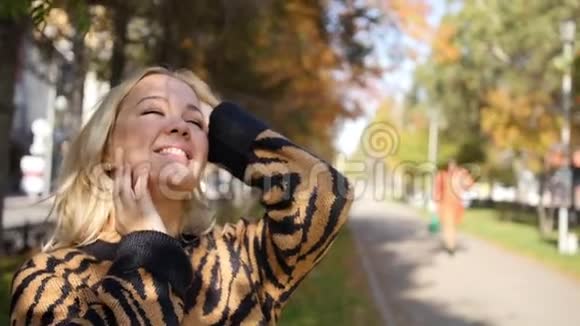 一位美丽的年轻女子在公园里欣赏秋天的肖像秋天公园里迷人的金发女郎视频的预览图