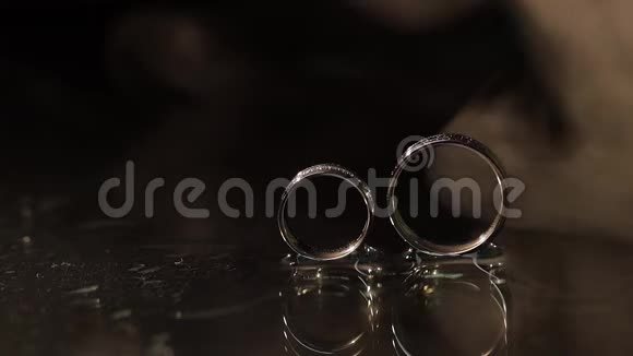 深色水面上的结婚戒指闪耀着光芒特写宏视频的预览图