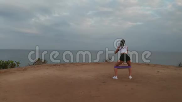 日出时在海边悬崖上运动的女人视频的预览图