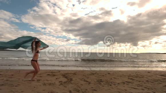 女人拿着围巾在海滩上奔跑视频的预览图